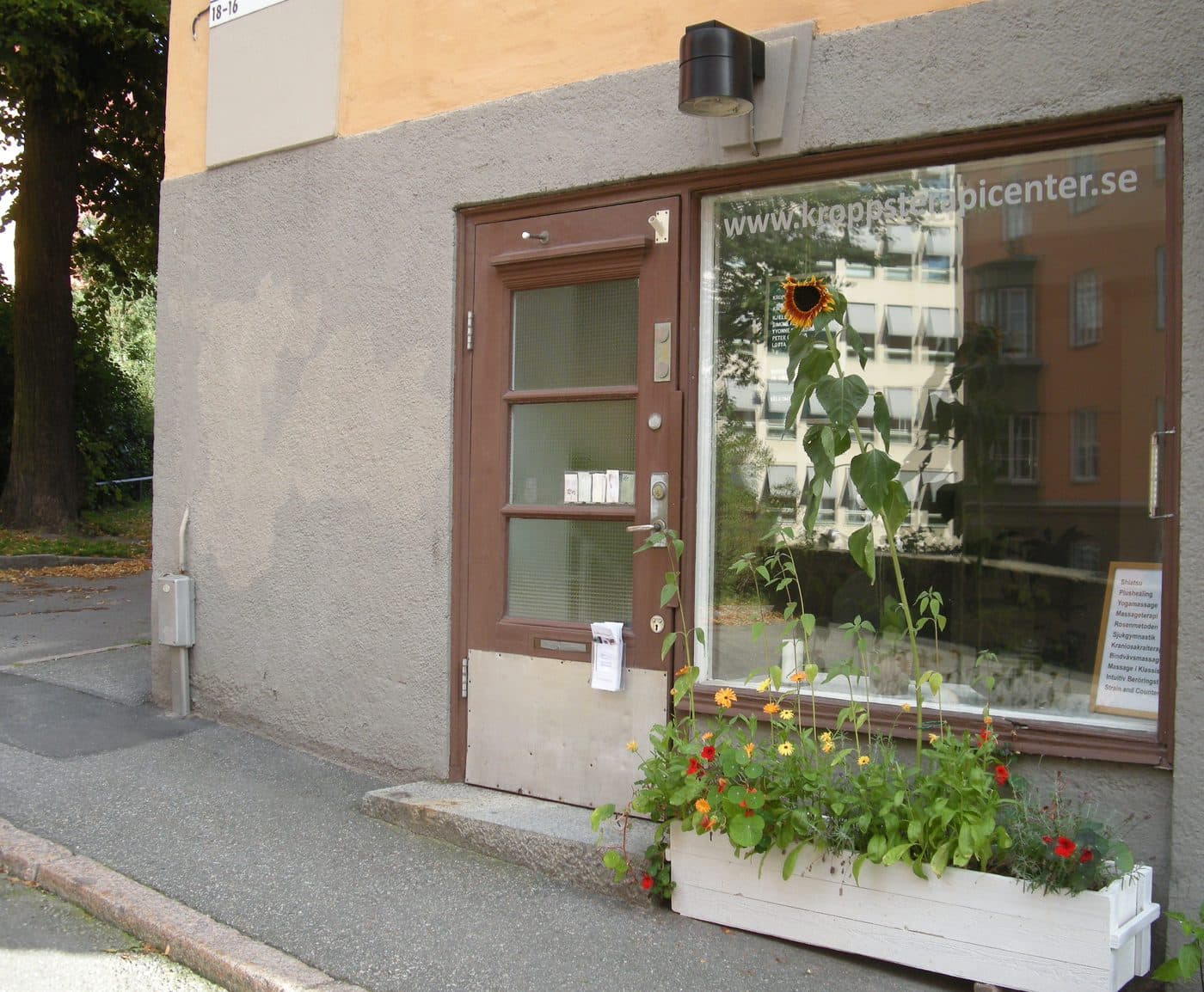 Entrén till Kroppsterapicenter på Torbjörn Klockares gata 18, med blomlåda utanför